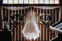 a wedding dress hangs on a wooden wall in a barn